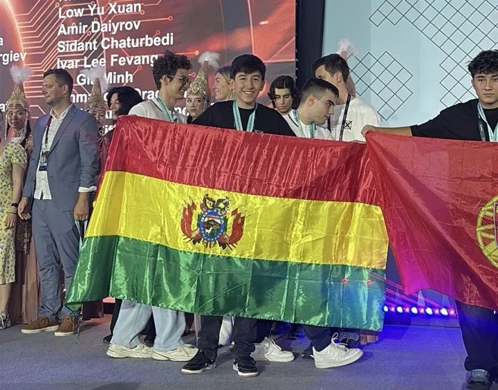 Estudiantes en el escenario de la premiación sostienen la bandera de Bolivia junto a otras delegaciones
